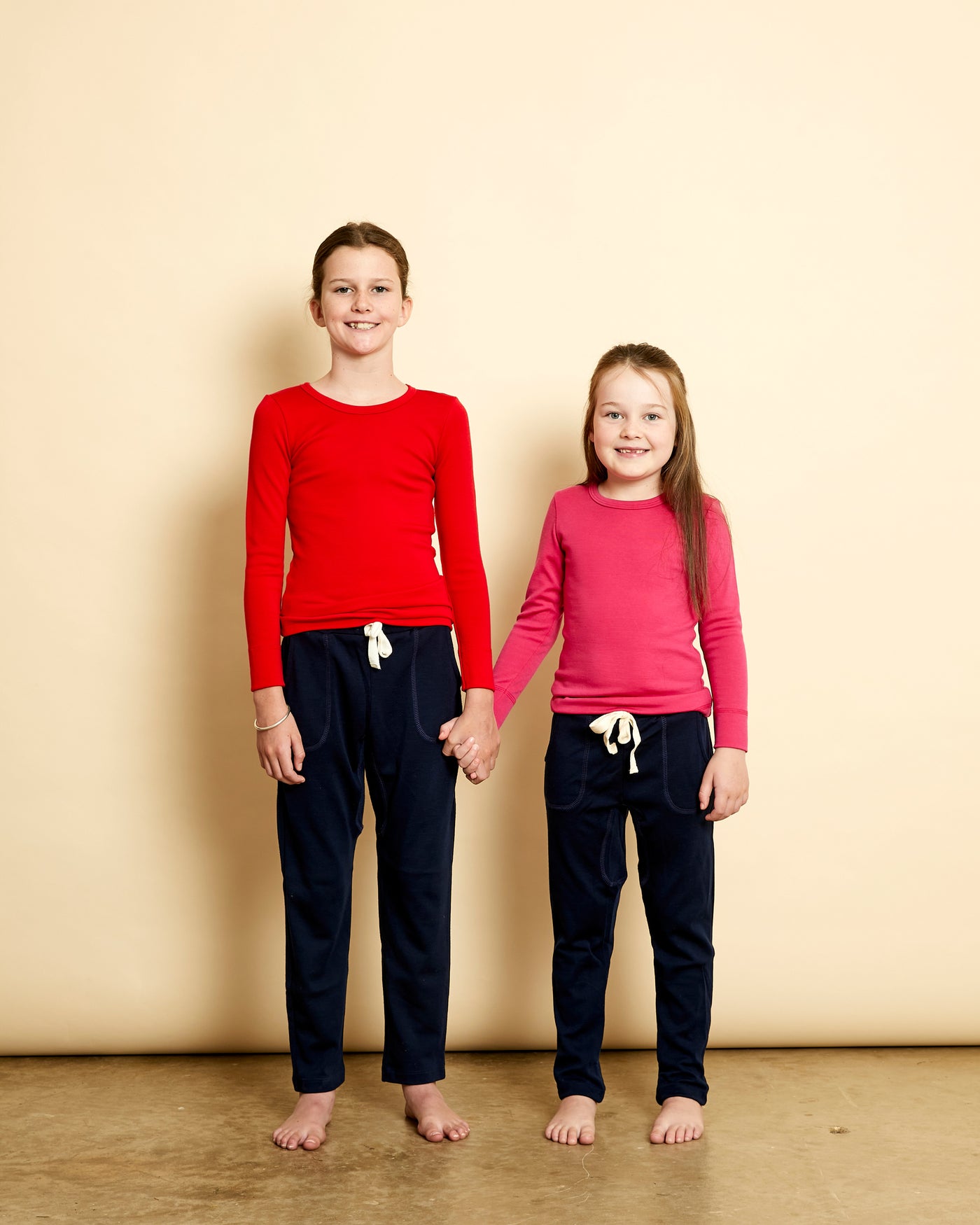 Girls wearing soft Australian Merino wool long sleeve crew neck in red and pink. Designed to wear next to the skin either as a base layer or as a t.shirt style on its own. This style is perfect for layering. Made in Australia at Woolerina's workrooms at Forbes in central west NSW.