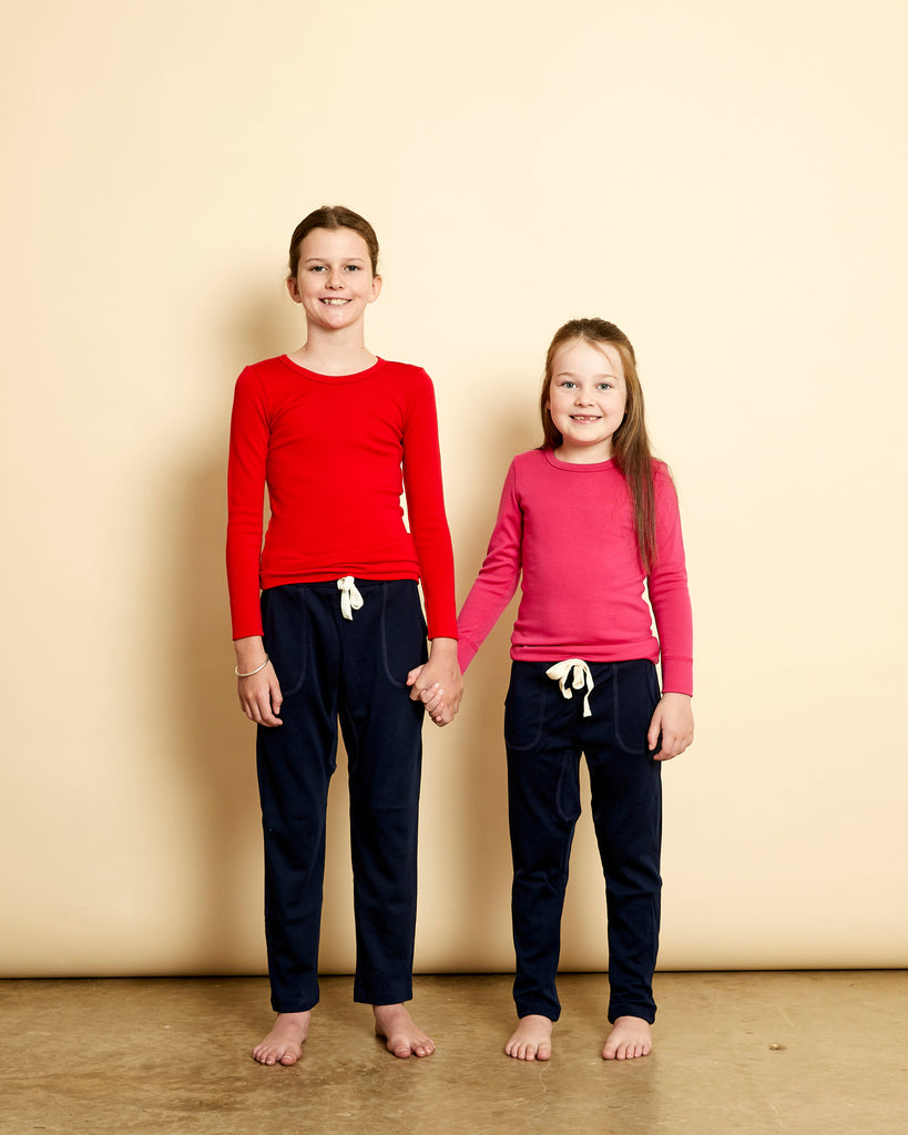 Girls wearing soft Australian Merino wool long sleeve crew neck in red and pink. Designed to wear next to the skin either as a base layer or as a t.shirt style on its own. This style is perfect for layering. Made in Australia at Woolerina's workrooms at Forbes in central west NSW.  Edit alt text