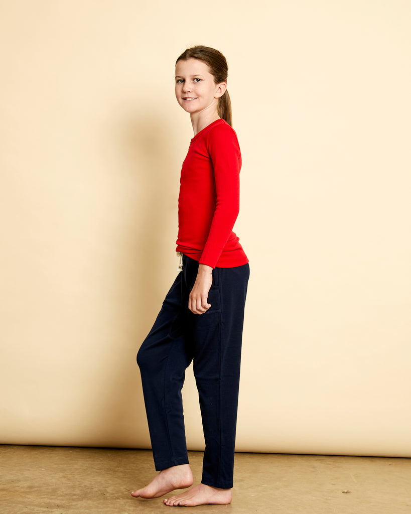 Girl wearing soft Australian Merino wool long sleeve crew neck in red. Designed to wear next to the skin either as a base layer or as a t.shirt style on its own. This style is perfect for layering. Made in Australia at Woolerina's workrooms at Forbes in central west NSW.  Edit alt text