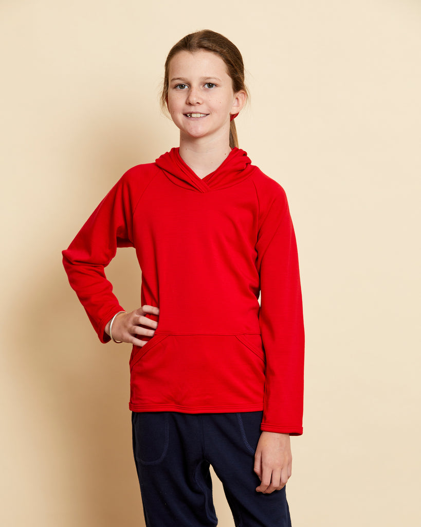 Girl wearing soft Australian Merino wool hoodie in red. Designed to wear over other layers as an outer layer. Made in Australia at Woolerina's workrooms at Forbes in central west NSW.