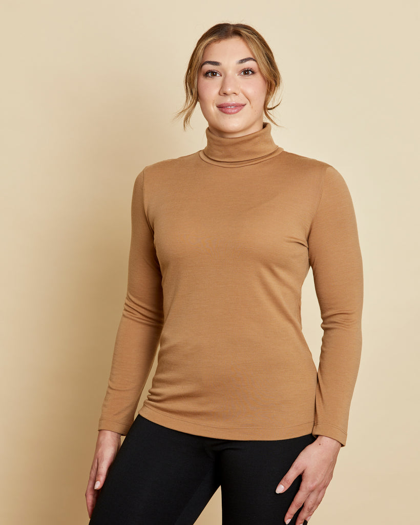 Woman wearing soft Australian Merino wool long sleeve turtleneck in camel. Designed to wear next to the skin as a base layer and also perfect for layering. Made in Australia at Woolerina's workrooms at Forbes in central west NSW.