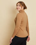 Woman wearing soft Australian Merino wool long sleeve turtleneck in camel. Designed to wear next to the skin as a base layer and also perfect for layering. Made in Australia at Woolerina's workrooms at Forbes in central west NSW.