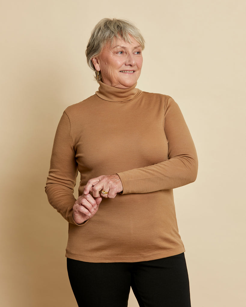 Woman wearing soft Australian Merino wool long sleeve turtleneck in camel. Designed to wear next to the skin as a base layer and also perfect for layering. Made in Australia at Woolerina's workrooms at Forbes in central west NSW.