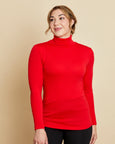 Woman wearing soft Australian Merino wool long sleeve turtleneck in tomato red. Designed to wear next to the skin as a base layer and also perfect for layering. Made in Australia at Woolerina's workrooms at Forbes in central west NSW.